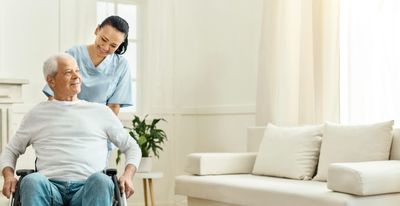 Female nurse helping man in wheelchair in his home